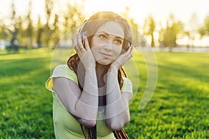 Modern woman with dreadlocks listening to music with her headphones in autumn Sunny Park. Concept of good mood