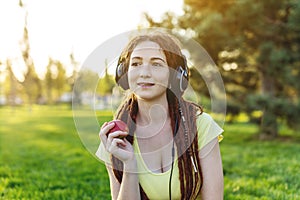 Modern woman with dreadlocks listening to music with her headphones in autumn Sunny Park. Melomania and good mood