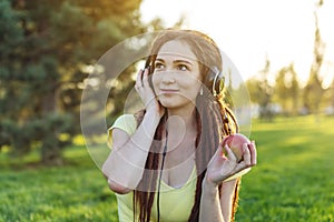 Modern woman with dreadlocks listening to music with her headphones in autumn Sunny Park. Melomania and good mood