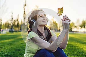 Modern woman with dreadlocks listening to music with her headphones in autumn Sunny Park. Melomania and good mood