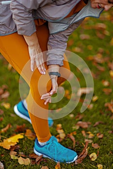 Modern woman in fitness clothes in park having leg pain