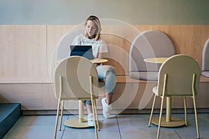 Modern woman freelancer working on a laptop at a table in a coworking space. Remote online work