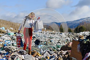 Modern woman on landfill with shopping bags. consumerism versus pollution concept.