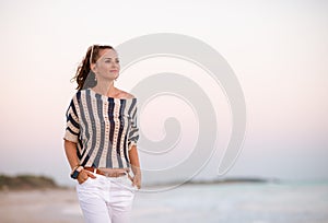 Modern woman on seacoast at sunset looking into distance