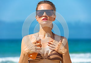 Modern woman on seashore applying SPF