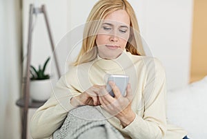 Modern woman surfing internet on phone, resting on sofa