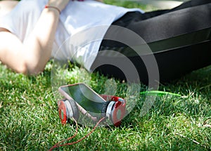 Modern woman, wireless headphones and smartphone on the grass