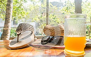 Modern women holiday essential for sunday summer time weekend activities on wooden table. Sunglasses placed over Books, flip flops