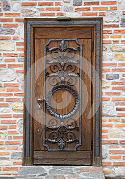 Modern wood door with antique wrought iron pattern installed in a brick wall, close-up