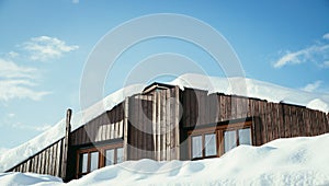 Modern wood house with windows and snow on the roof, blue sky with text space