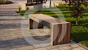 Modern wooden benches on the lawn in the park. Stylish new bench in city recreation area on sunrise or sunset. Urbanism