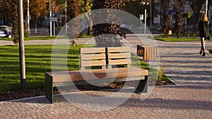 Modern wooden benches on the lawn in the park. Stylish new bench in city recreation area on sunrise or sunset. Urbanism