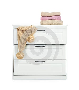 Modern wooden chest of drawers with clothes on white