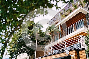 A modern wooden cottage with large balconies among tall trees.