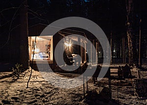 Modern wooden log cabin and snow covered trees in winter Finland Lapland. Secluded tiny house. Private house near forest