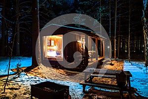 Modern wooden log cabin and snow covered trees in winter Finland Lapland. Secluded tiny house. Private house near forest