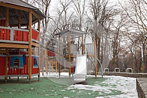 Modern wooden playground for young children during winter season. Wooden house with slides