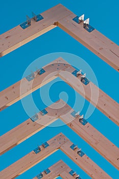 Modern wooden roof frame or frames, framework with trusses on a renovated house. Blue sky in the background