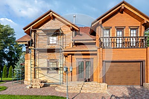 Modern wooden timber eco house villa facade during process of renovation, sanding wall for varnishing against sun burn