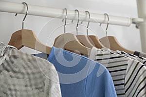 Modern wooden wardrobe with clothes hanging on rail