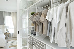 Modern wooden wardrobe with clothes hanging on rail