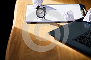 Modern workplace, wooden office desk in hardlight, sunligt with clock, sheet of paper