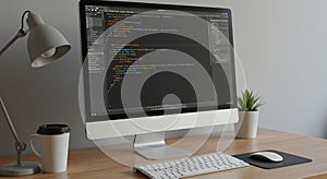 A modern workspace features a computer monitor displaying programming code. The