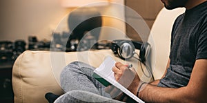 Left handed man writing, sitting on a sofa