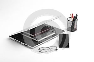 Modern workspace with laptop keyboard, notebook, spectacles on white background