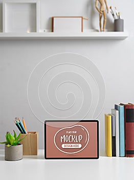 Modern worktable with mock up tablet, books, stationery and decorations in home office room
