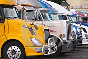 Modern yellow semi truck on foreground of other trucks