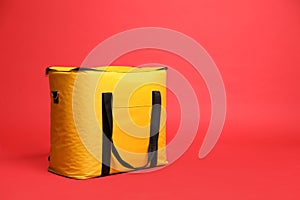 Modern yellow thermo bag on red background. Space for text