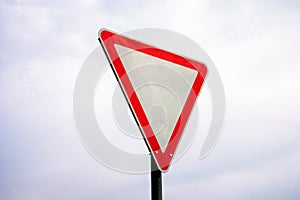 Modern yield sign against cloudy sky