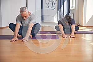 Modern yogis doing a stretching exercise indoors