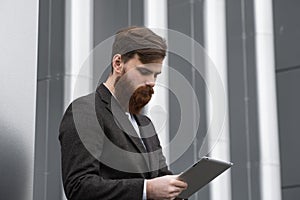 Modern Young bearded Business man working with a digital tablet. Young hipster businessman holding tablet in hands
