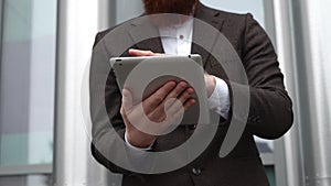 Modern Young bearded Business man working with a digital tablet. Young hipster businessman holding tablet in hands