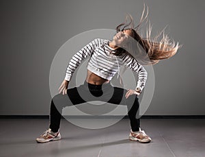 Modern young beautiful dancer posing on a studio background