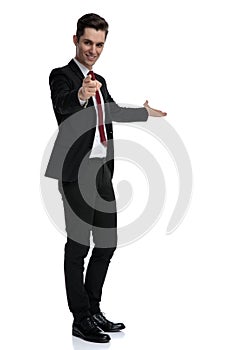 Modern young businessman presenting and pointing forward