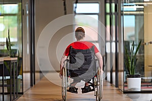 A modern young businesswoman in a wheelchair is surrounded by an inclusive workspace with glass-walled offices