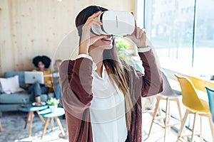 Modern young entrepreneur woman using virtual reality headset and enjoying the moment in a coworking place