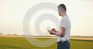 Modern Young Farmer using digital tablet on agricultural field.