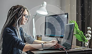 Modern young female programmer is writing program code on a laptop at home. The concept of software development