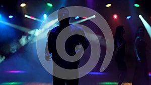 A modern young guy dances in the dark in nightclub