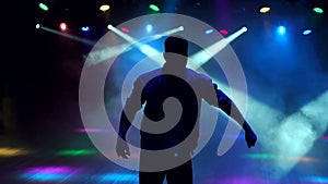 A modern young guy dances in the dark in nightclub