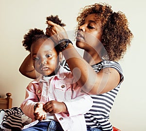 Modern young happy african-american family: mother combing daughters hair at home, lifestyle people concept