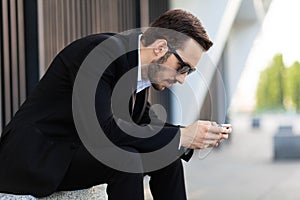 Modern young man playing on phone, browsing mobile news. Gadget Dependence