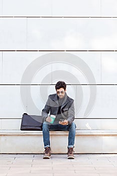 Modern young man using his mobile phone in the street.