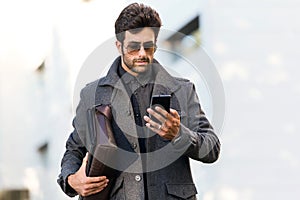 Modern young man using his mobile phone in the street.