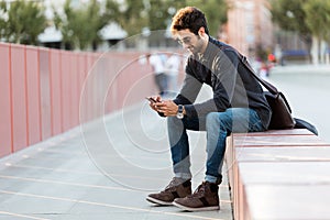 Modern young man using his mobile phone in the street.