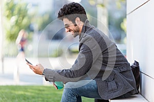 Modern young man using his mobile phone in the street.